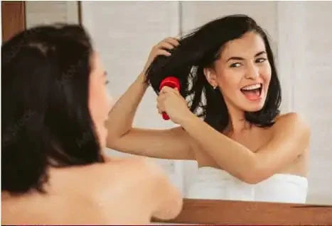 happy woman in towel brushing hair in front of mirror
